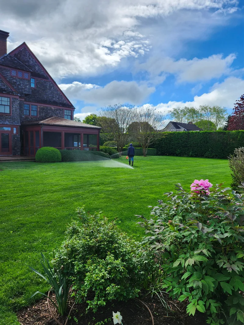 Sprinklers operating across a green lawn at a Hamptons property.