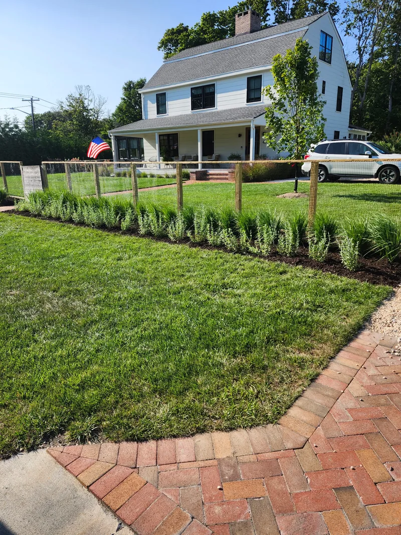 Finished lawn and planting bed along a split-rail fence.